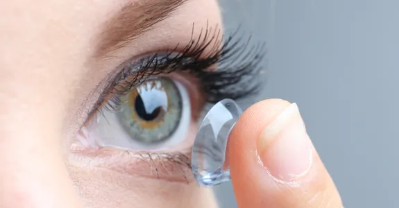 Photo of woman putting on contact lens.
