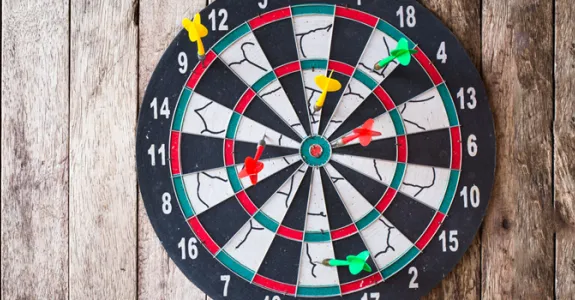 Photo of a dart board with several darts in it.