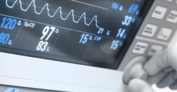 Graphic image showing a gloved hand adjusting a dial on a hospital room display screen.