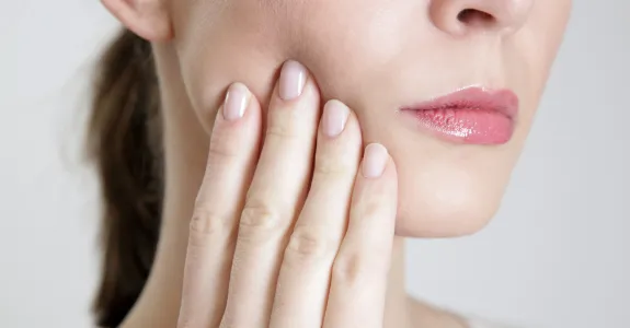Stock photo of a woman touching her cheek.