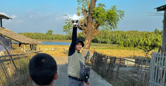 A local drone pilot, Muh. Yusuf Fadhel Marwiji, in Makassar, Indonesia, prepares to launch a drone to search for discarded tires that collect rainwater and become mosquito breeding sites, as a curious child watches