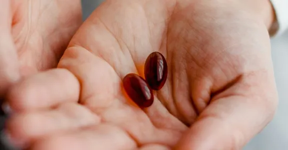 Photo of cupped hands with two large orange-brown pills held in the palms.