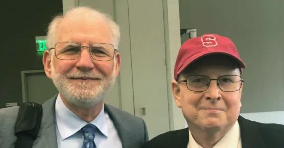 Photo of elder doctor and middle-aged man wearing a red hat.