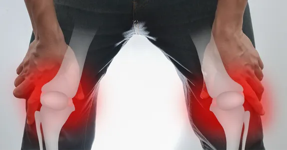 Photo of a man holding his knees, with 3D superimposed structure of his bones with red around the knees to show inflammation.