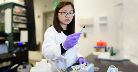 Photo of postdoctoral scholar Chong Liu examining a carbon-amidoxime electrode in the laboratory.