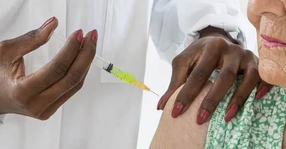 Photo of an older woman receiving a vaccination injection in the shoulder.