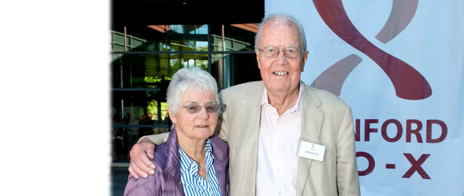 Photo of Bill and Ute Bowes in front of a banner with Stanford Bio-X logo.