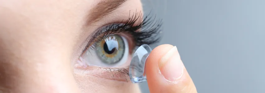 Photo of woman putting on contact lens.