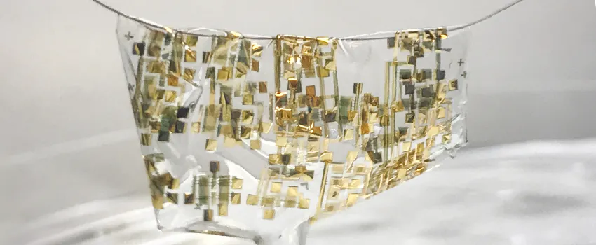 Photo showing the extremely flexible semiconductor draped liquid-like over a human hair, with gold sensors dispersed throughout transparent semiconductor material.