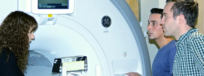 Photo of Professor Kalanit Grill-Spector, research associate Kevin Weiner, and graduate student Jesse Gomez next to MRI machine.