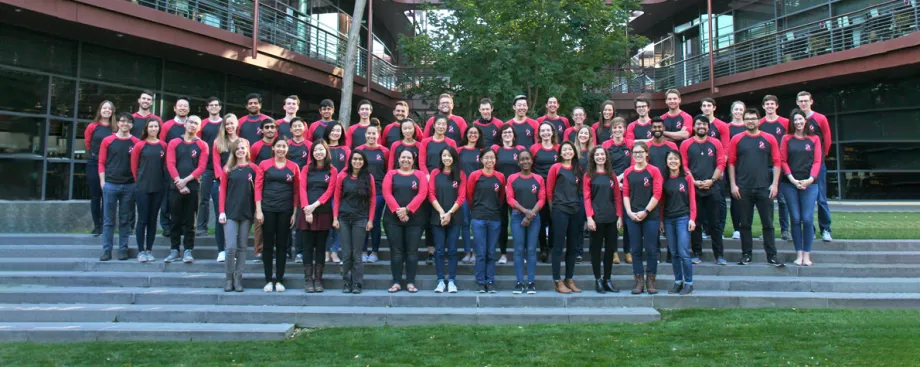 Photo of dozens of Stanford Bio-X PhD Fellows standing together in matching dark gray and red shirts.
