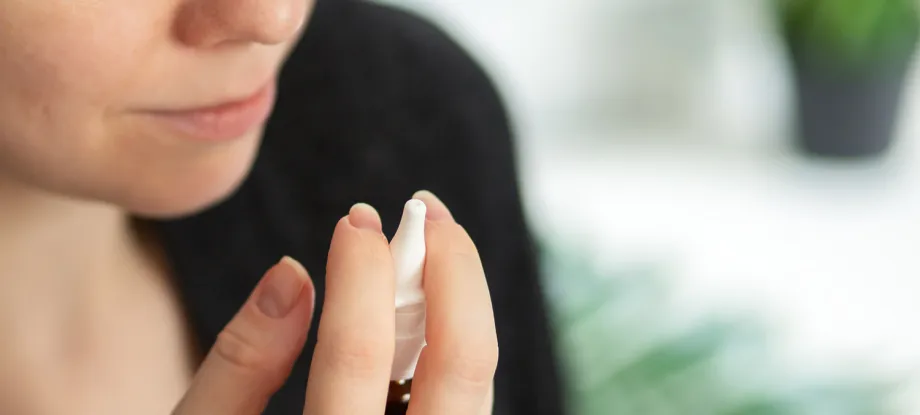 Photo of a woman raising a nasal spray in her hand.