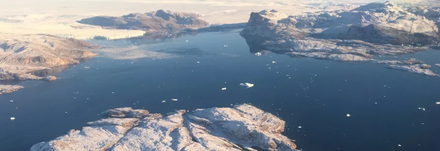 Large body of water in Greenland, broken by islands, with snowmelt visible.