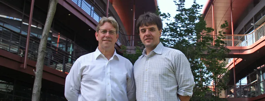 Outdoor photo of two male faculty members standing together and smiling.