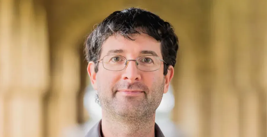 Photo of a white male faculty member in glasses standing in one of Stanford's arcades.