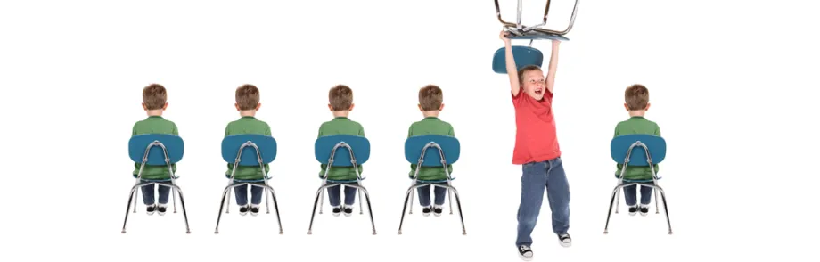 Photo of line of children sitting in chairs, with one child acting out.