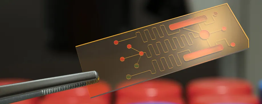 Photo of a pair of tweezers holding up a small microfluidics chip.