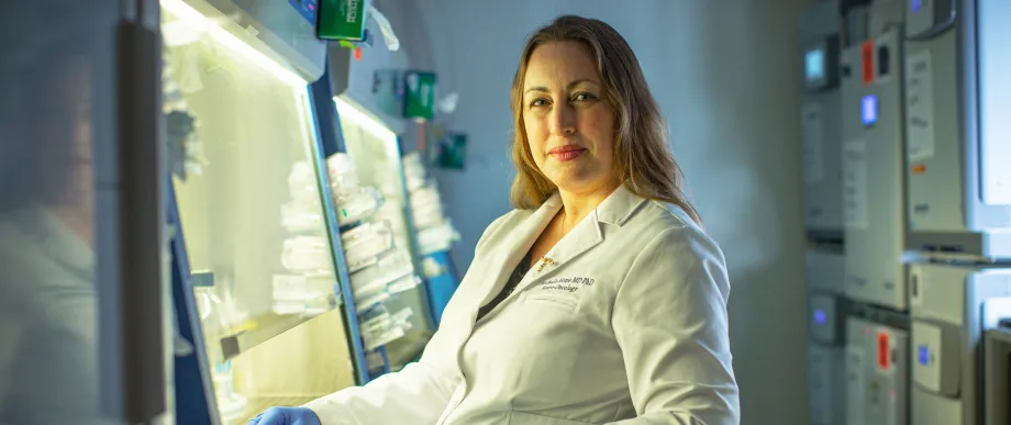 Photo of Dr. Michelle Monje seated in the laboratory, wearing a lab coat.