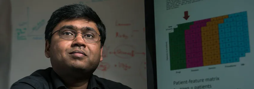 Photo of Dr. Nigam Shah with a graph on the projector behind him.