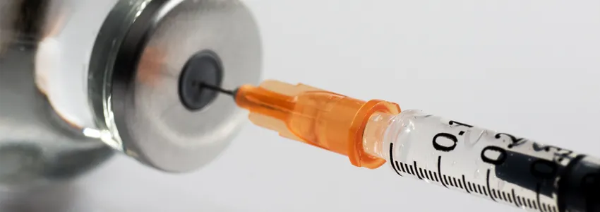 Photo of a needle going into a vaccine container.