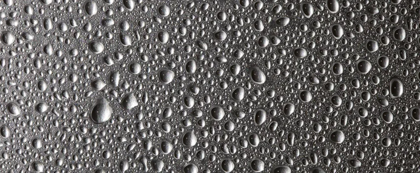 Image of water droplets of varying sizes on a gray background.