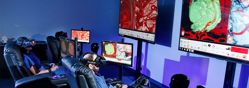 Photo of two surgeons sitting in armchairs, wearing virtual reality headsets in front of large monitors displaying surgery images.