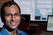 Photo of Dr. Sanjay Basu sitting in office, with computer screens in the background.